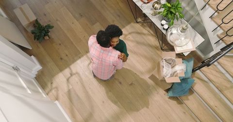 Friends joyfully unpacking in new home, embracing and organizing together