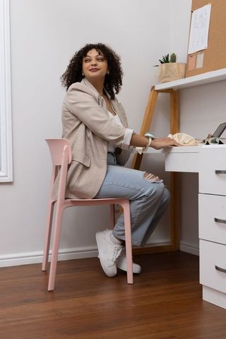 Confident african american woman working at home desk in casual blazer and ripped jeans