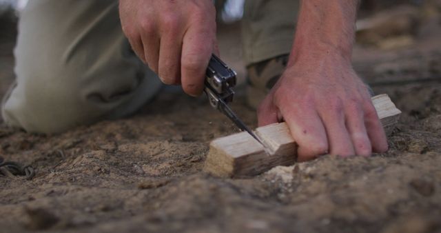 Caucasian male survivalist cutting notch in fireboard at camp in wilderness. exploration, travel and adventure, survivalist in nature.