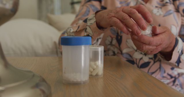 Mid section of caucasian senior woman removing pills from medicinal containers at home. retirement senior lifestyle living concept