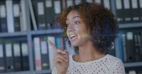 Businesswoman pointing at digital stock chart overlay presenting financial data in office