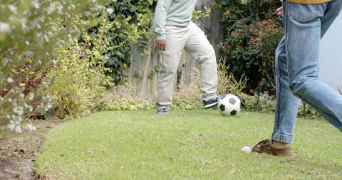 Playing soccer in backyard casual kick on green lawn between two people