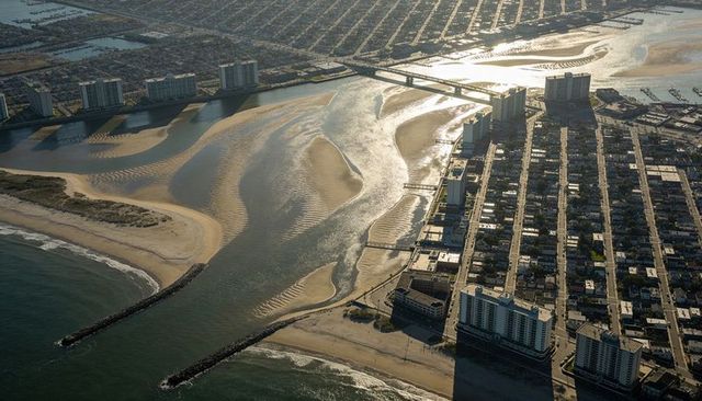 Aerial coastline revealing sandbars, jetties, bridge and waterfront towers at low tide