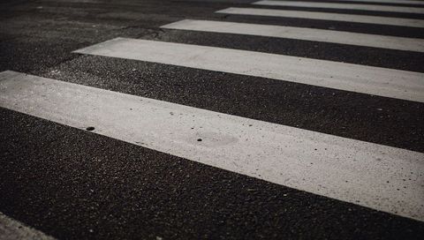 Close-up of weathered crosswalk stripes on asphalt showcasing diagonal perspective, texture