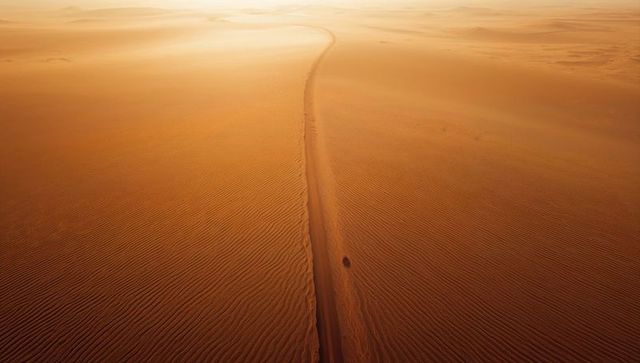 Serene desert track at golden hour with rippled sand patterns