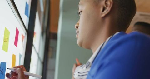 Man Brainstorming with Sticky Notes on Office Glass Wall