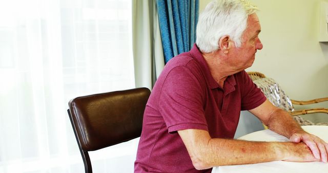 Senior Man Sitting at Table Inside Home Looking Sideways - Download Free Stock Images Pikwizard.com