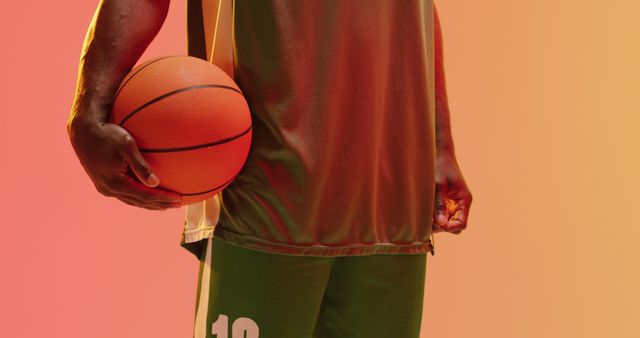 Image of midsection of african american male basketball player holding ball on orange background - Download Free Stock Photos Pikwizard.com