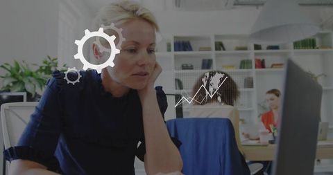 Businesswoman analyzing data with digital gear icons in office