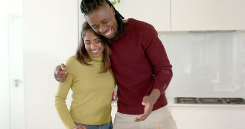 Couple cooking together in bright modern kitchen sharing warmth, affection and joy