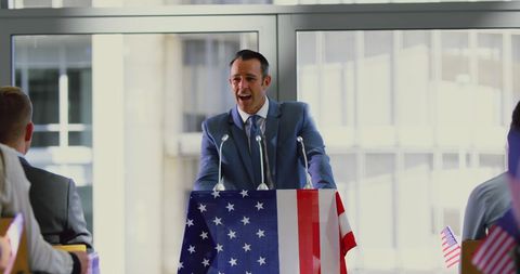 Politician speaking at american flag podium during rally