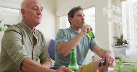Father and Son Enjoying Refreshments Watching Television at Home