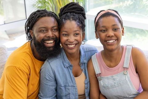 Joyful african american family smiling on sofa in bright living room wearing casual denim