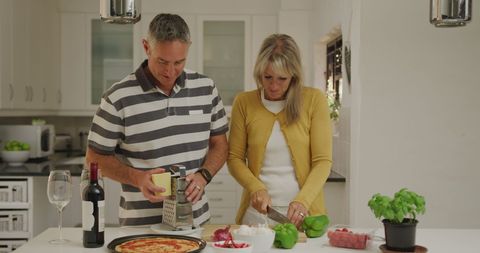 Happy couple collaborating in modern kitchen making pizza