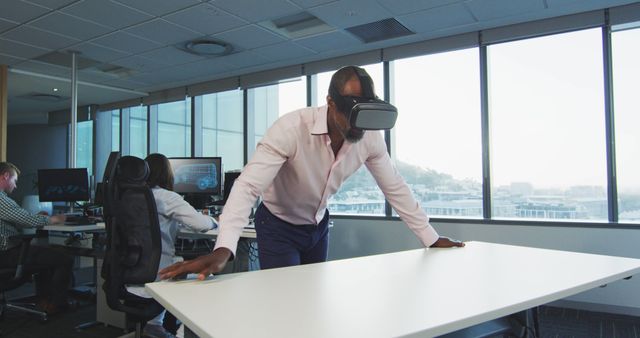 Middle-aged man using virtual reality headset in a contemporary office with large windows, exploring immersive technology for business innovation. Suitable for illustrating tech adoption in corporate settings, modern workplace concepts, and presentations about future work environments.