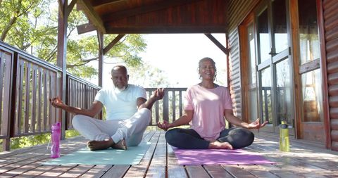 Senior african american couple meditating outdoors on porch