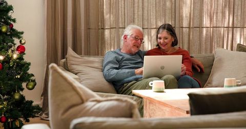 Senior couple enjoying laptop time near christmas tree at home