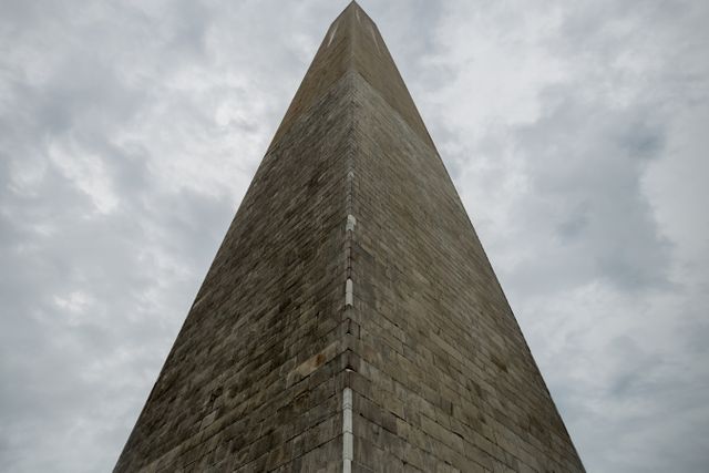 This image features a granite obelisk captured from a low-angle perspective with a cloudy sky in the background. Great for illustrating historic landmarks, architectural designs, and travel destinations.