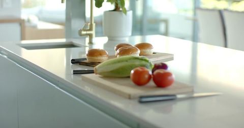 Sunlit minimalist kitchen island showcasing fresh tomatoes, lettuce and brioche buns