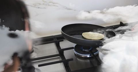 Woman flipping pancake on gas stove, steaming skillet and morning kitchen routine