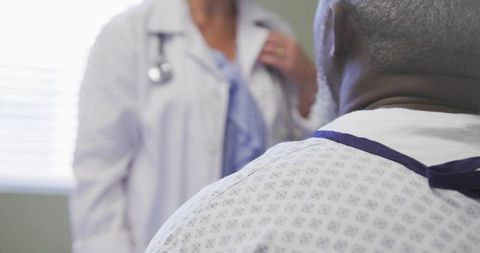Doctor Consulting Senior Male Patient in Clinic Gown During Medical Examination