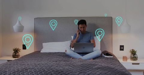 Remote worker calling and typing on laptop in bedroom with virtual location pins