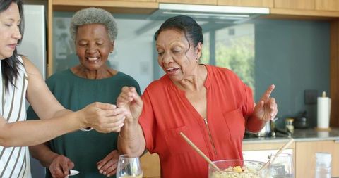 Multigenerational women cooking together in modern kitchen sharing fresh salad joy