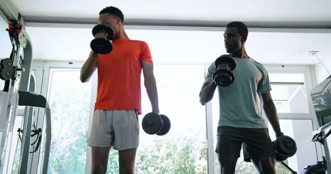 Men lifting dumbbells in gym focusing on strength training