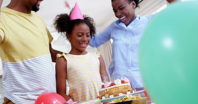 Family enjoying birthday celebration at home with little girl. Ideal for content focusing on family bonds, joyous events, and special moments. Useful for articles, advertisements, and promotions related to family gatherings, birthdays, and home celebrations.