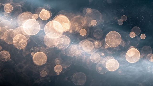 Glowing golden bokeh orbs forming shimmering diagonal band over smoky dark backdrop