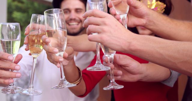 Group of friends clinking champagne glasses in celebration, showcasing happiness and togetherness. Ideal for use in articles about celebrations, parties, friendship, and festive events.
