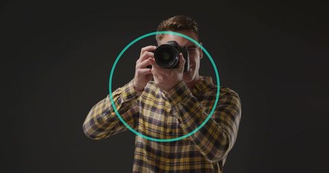 Young photographer framing shot with dslr in yellow plaid shirt and teal overlay