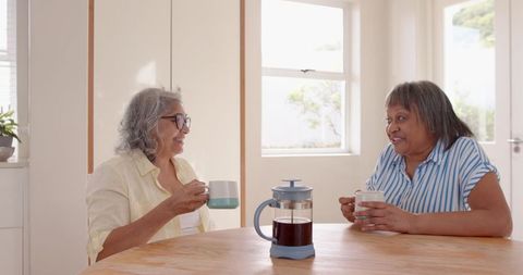 Senior Women Conversing Over Coffee at Home, Smiling Together