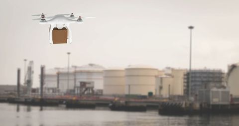 Delivery drone hovering with package in industrial port