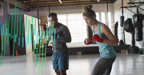 Woman practicing boxing sparring with coach in industrial gym during intense training