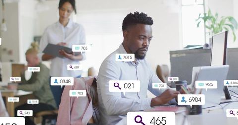 Black professional working on laptop in modern open-plan office analyzing data