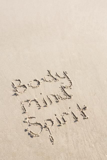 Text 'Body Mind Spirit' written on sand at beach, conveying themes of wellness, mindfulness, and holistic balance. Ideal for use in wellness blogs, motivational posters, self-care websites, and inspirational social media posts.