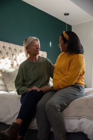 Comforting connection between senior woman and caregiver holding hands on bed