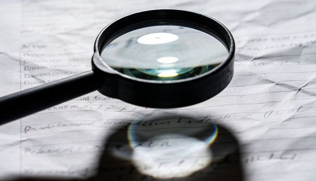 Magnifying Glass Casting Color Fringe Over Handwritten Paper with Shadow and Reflection