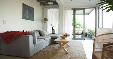 Sunlit minimal living room with light-gray l-shaped sofa and wooden coffee table