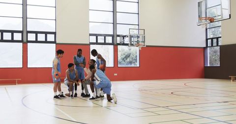 Inclusive Basketball Team Huddling with Coach Indoors