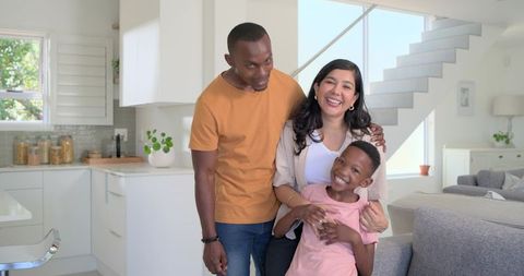 Smiling parents embracing son in bright modern open-plan kitchen and living room