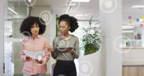 Businesswomen Walking with Digital Icons in Modern Office