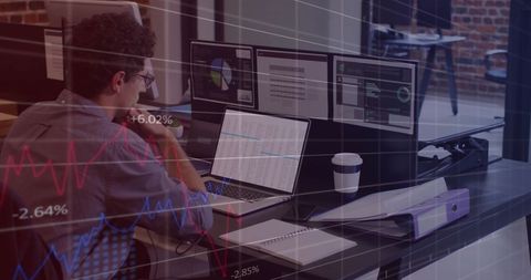 Businessman analyzing financial data on multiple screens in modern office