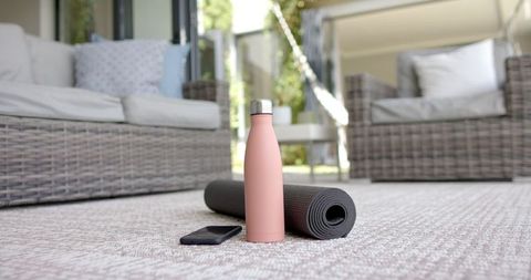 Yoga Mat with Bottle and Phone Outdoors in Relaxing Patio Environment