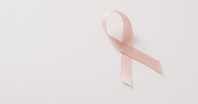 Pink ribbon symbolizing breast cancer awareness laid against a white background. Ideal for use in healthcare and awareness campaigns, presentations about breast cancer, support groups, medical brochures, and social media posts dedicated to breast cancer prevention and advocacy.