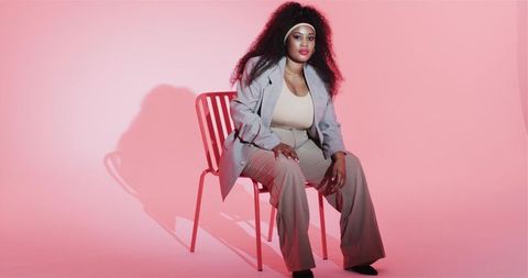 Stylish woman in modern outfit poses in vibrant studio setting