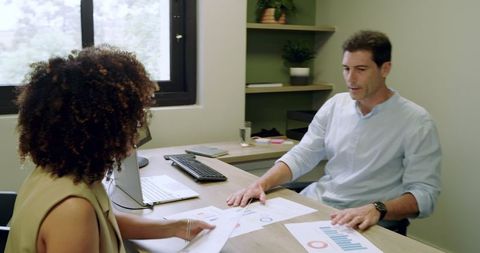 Coworkers Collaborating Over Financial Charts in Office