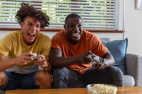 Diverse Friends Enjoying Video Gaming on Sofa with Snacks
