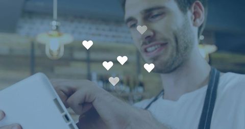 Barista using tablet with heart icons overlay showing customer feedback in cozy cafe